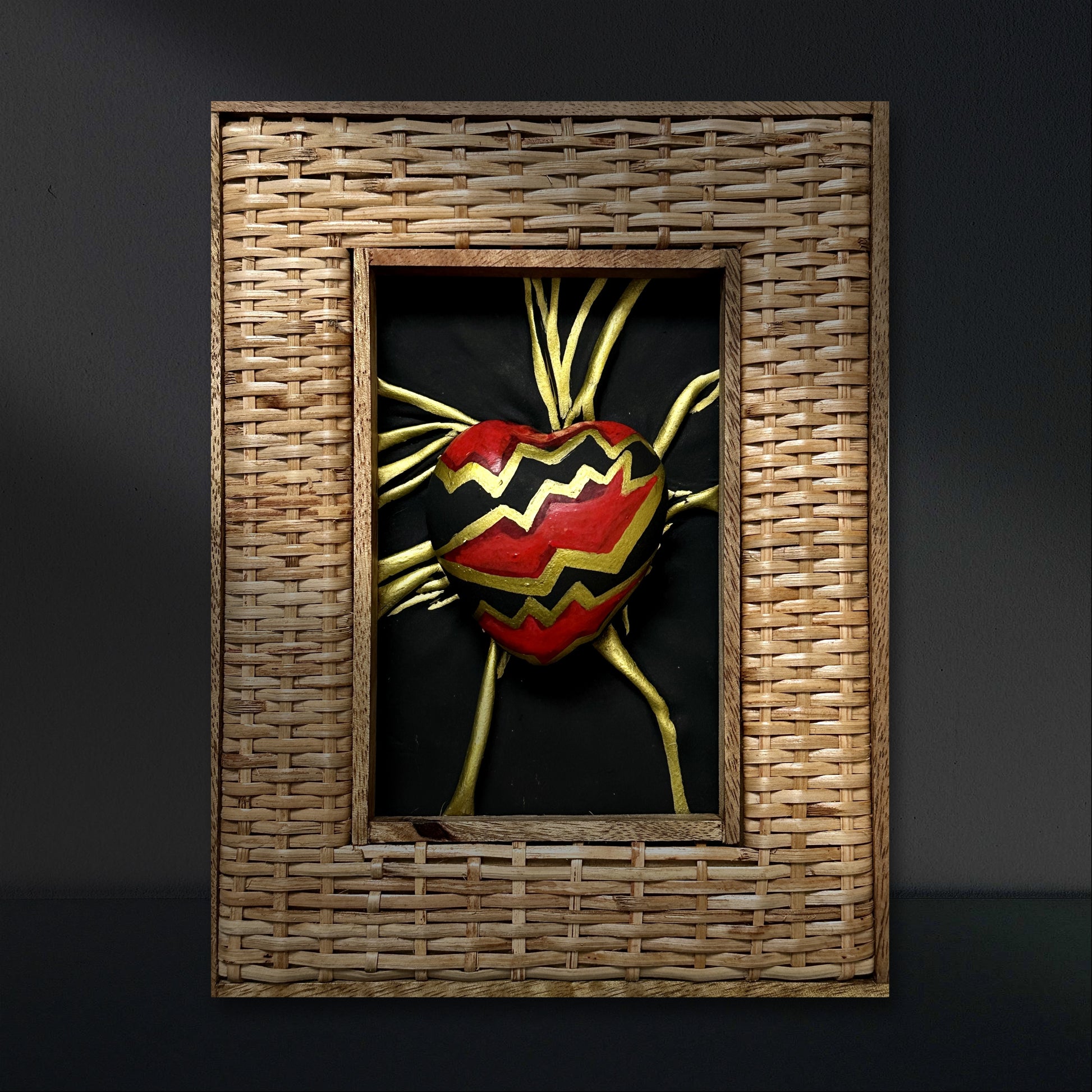 Genuine leather heart sculpture, adorned with bold black, red, and gold acrylic paint details, elegantly framed for display.