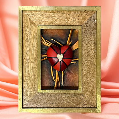 Genuine leather heart sculpture adorned with vibrant black, red, and gold details, in a sophisticated wooden frame.