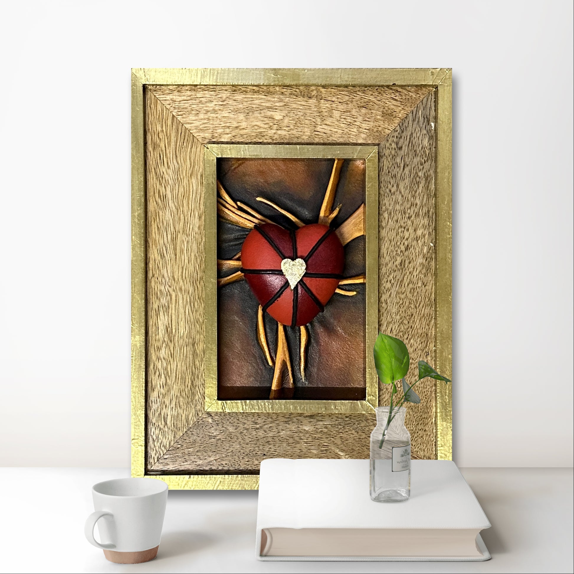 Unique leather heart artwork, hand-painted with bold black, red, and gold accents, displayed in a gold leaf-finished frame.