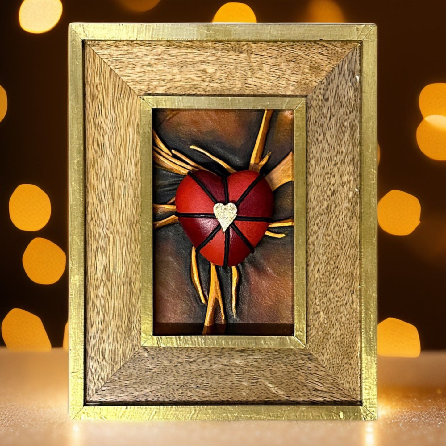 Handcrafted leather heart sculpture with striking black, red, and gold details, framed in a luxurious gold leaf-finished frame.